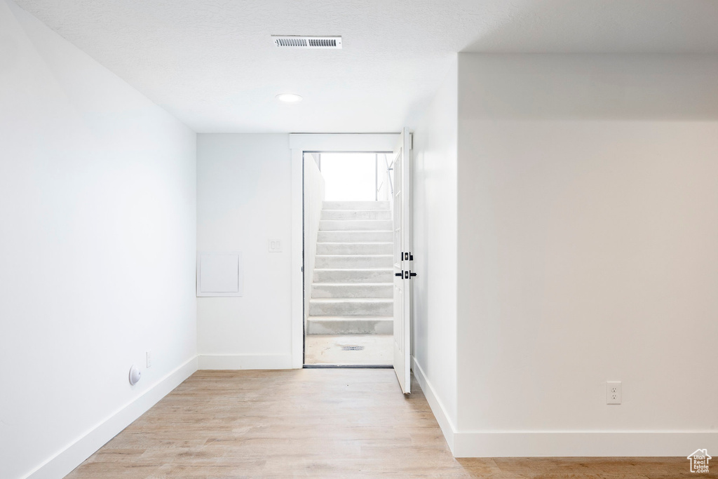 Empty room featuring stairs, light wood-style floors, and recessed lighting