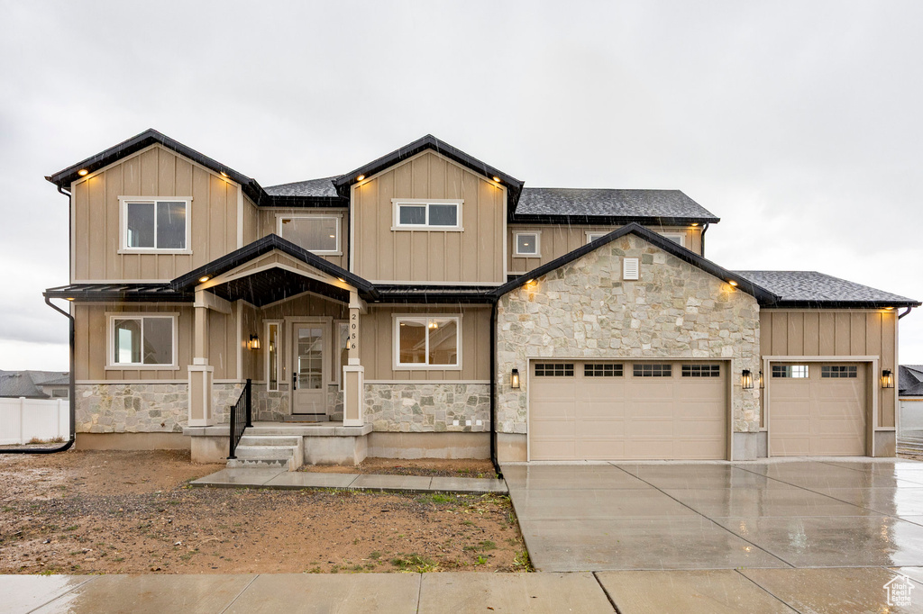 Craftsman house with stone siding, concrete driveway, a garage, and board and batten siding