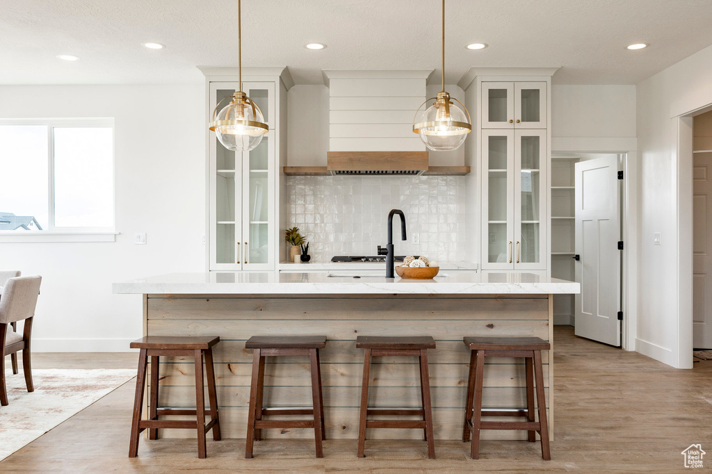 Kitchen with a center island with sink, backsplash, recessed lighting, a breakfast bar area, and pendant lighting