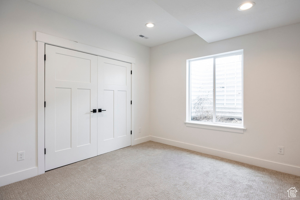 Unfurnished bedroom featuring light carpet, recessed lighting, and a closet
