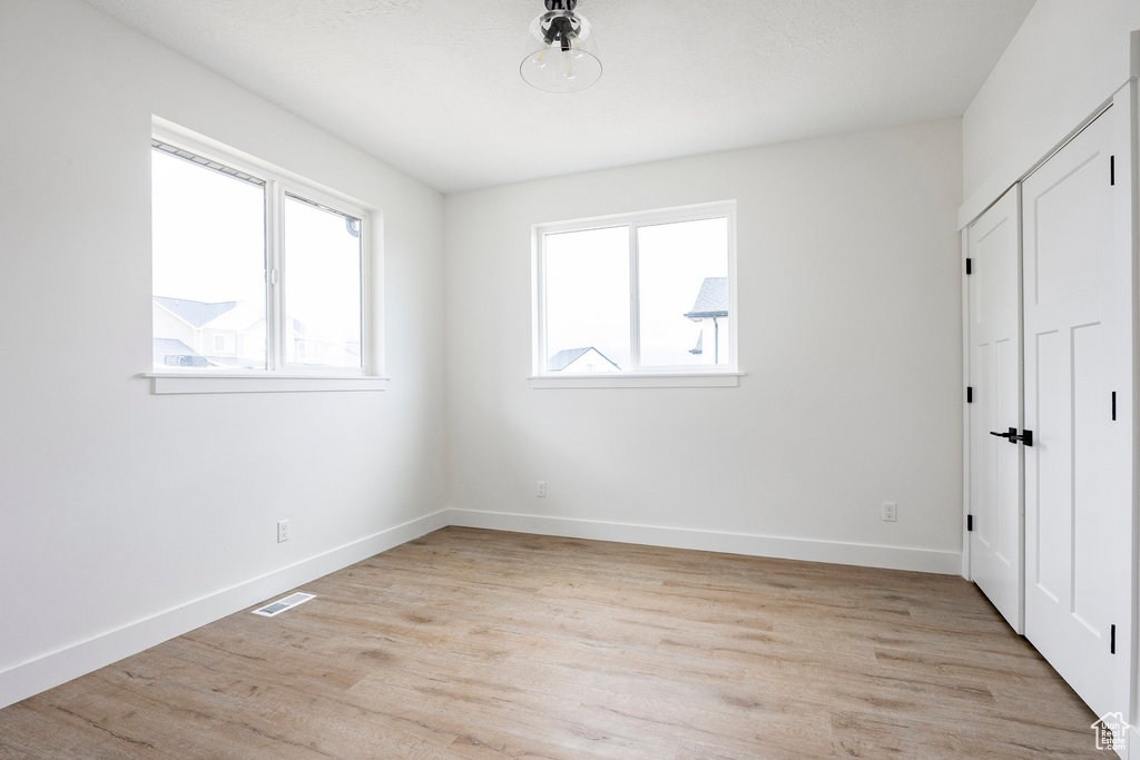 Unfurnished bedroom featuring light wood finished floors and a closet