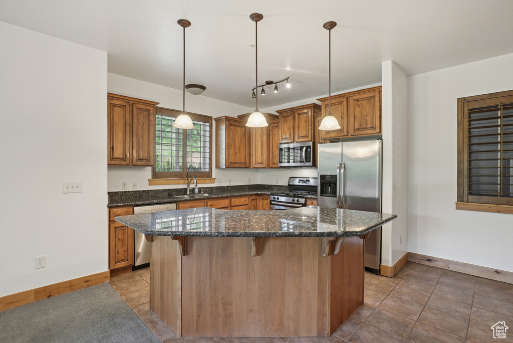 Kitchen featuring appliances with stainless steel finishes, a kitchen breakfast bar, brown cabinets, and tile patterned flooring