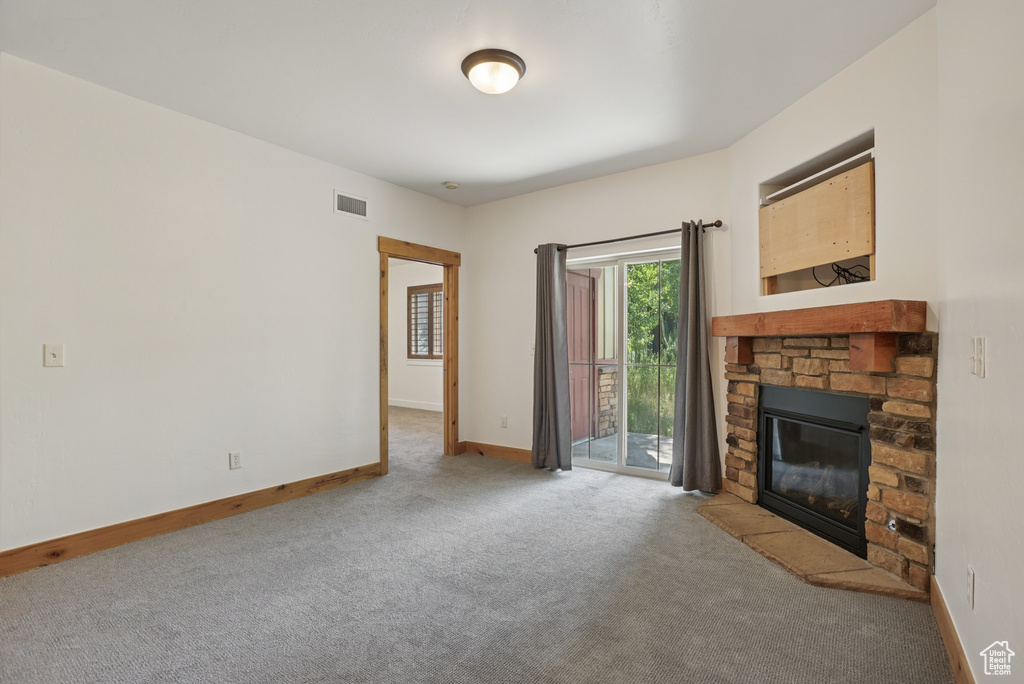 Unfurnished living room with carpet and a stone fireplace
