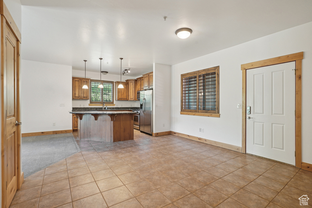 Kitchen with appliances with stainless steel finishes, a kitchen bar, dark countertops, decorative light fixtures, and a kitchen island