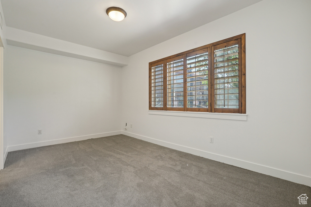 Spare room with baseboards and dark colored carpet