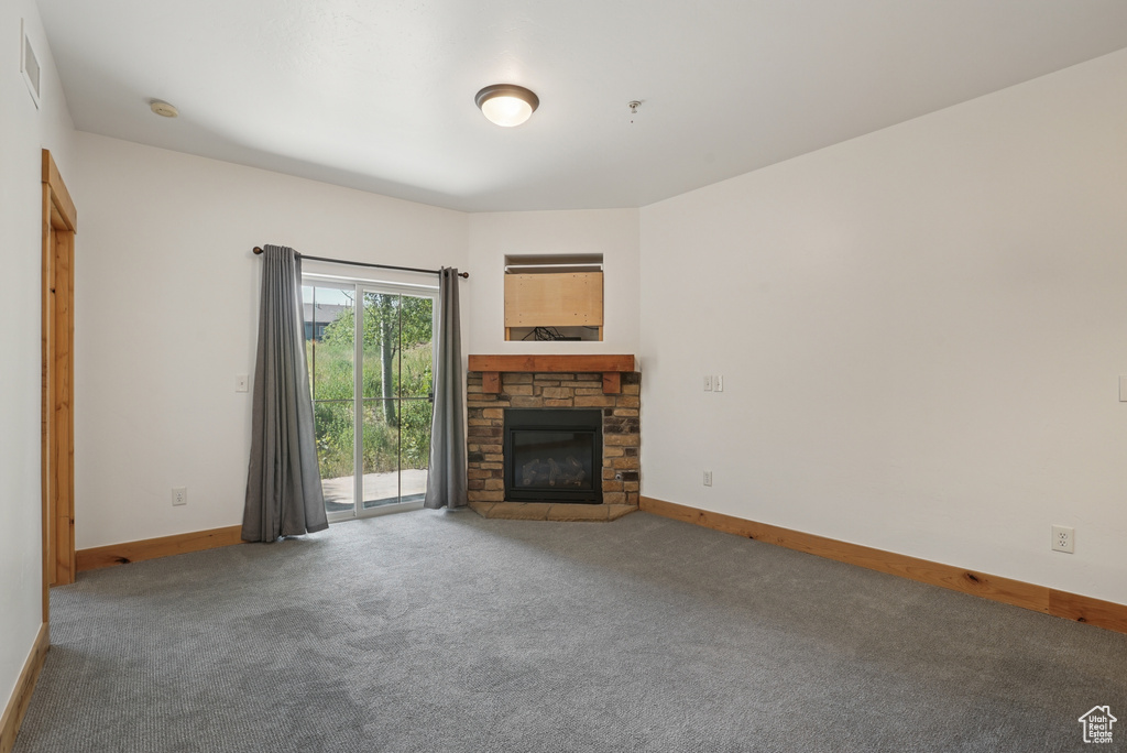 Unfurnished living room with carpet flooring and a stone fireplace
