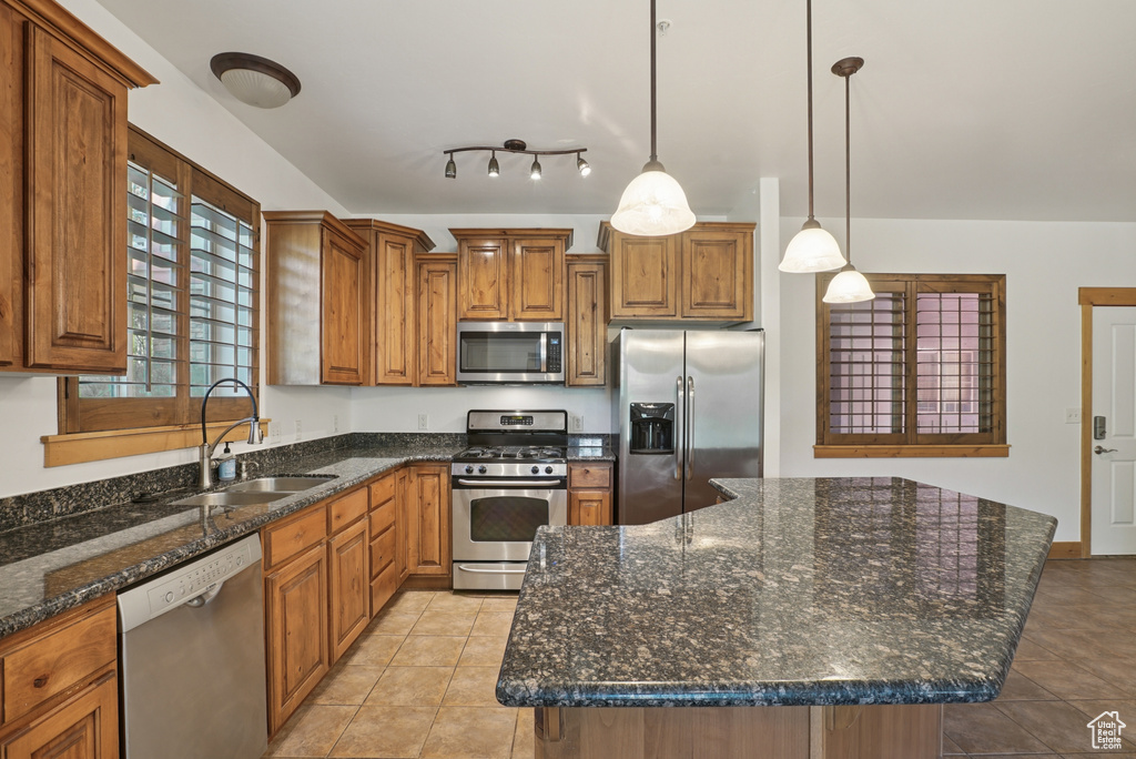 Kitchen featuring appliances with stainless steel finishes, brown cabinets, and light tile patterned floors