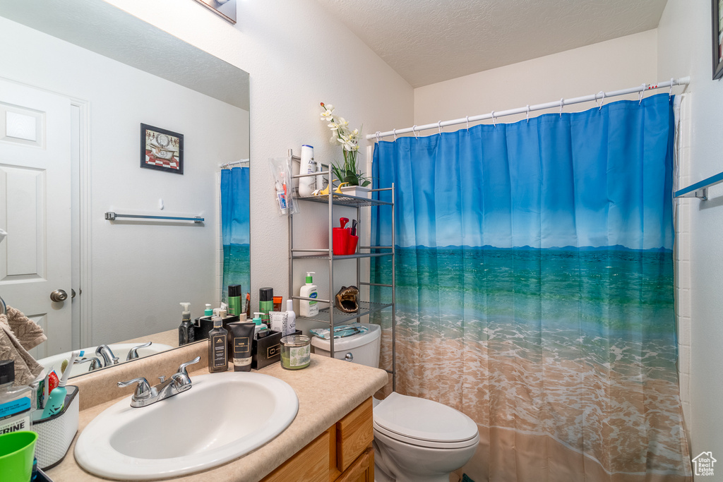 Bathroom with vanity, a textured ceiling, and a shower with shower curtain