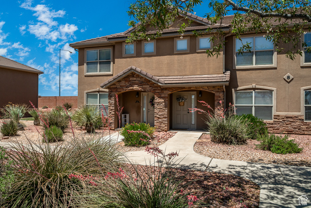Multi unit property with stucco siding, stone siding, and a tiled roof