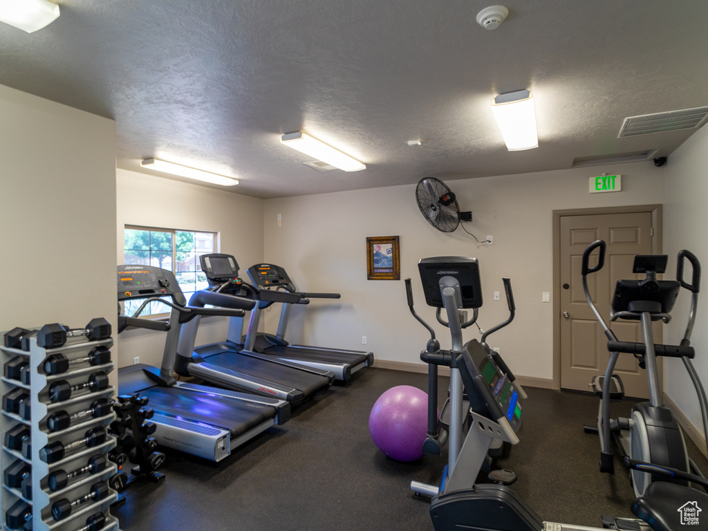 Exercise room with a textured ceiling and baseboards