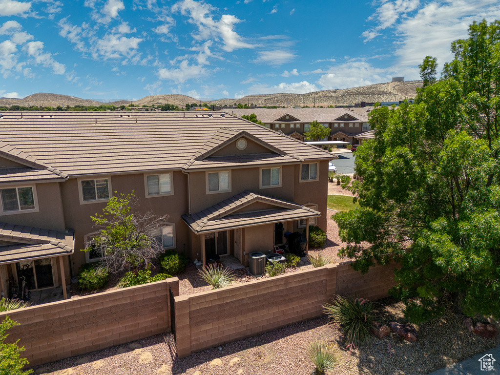 Rear view of property featuring a mountain view, a fenced front yard, stucco siding, and a tiled roof