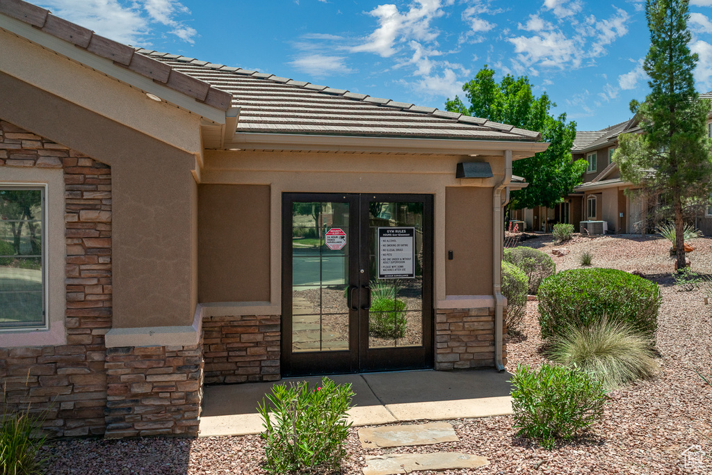 Doorway to property featuring stone siding, french doors, a tiled roof, and stucco siding