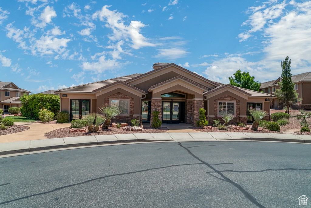 View of front of home featuring french doors, a tiled roof, stucco siding, and stone siding
