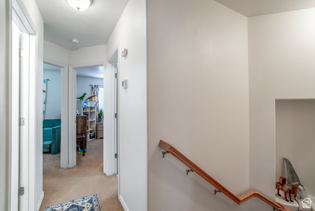 Corridor featuring light colored carpet and an upstairs landing