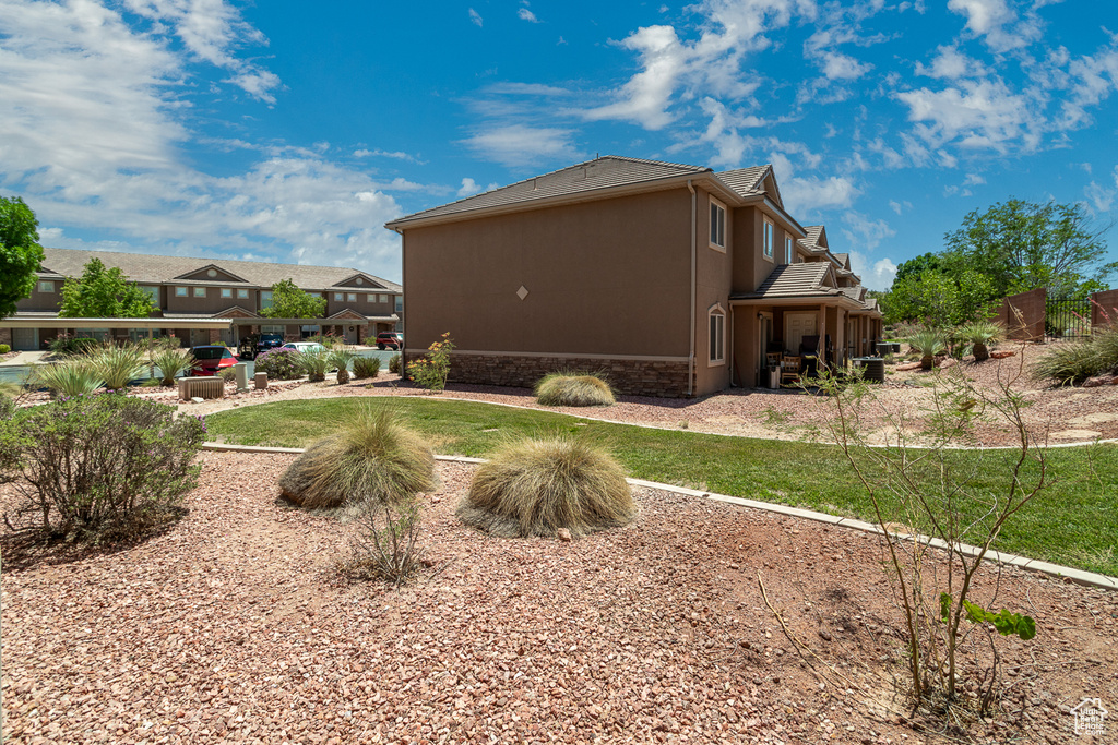 Rear view of house with stone siding, a patio, stucco siding, a tile roof, and a yard