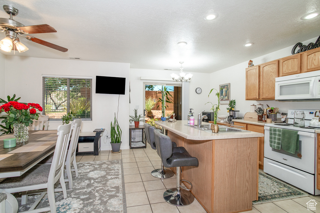 Kitchen featuring white appliances, healthy amount of natural light, light countertops, a chandelier, and recessed lighting