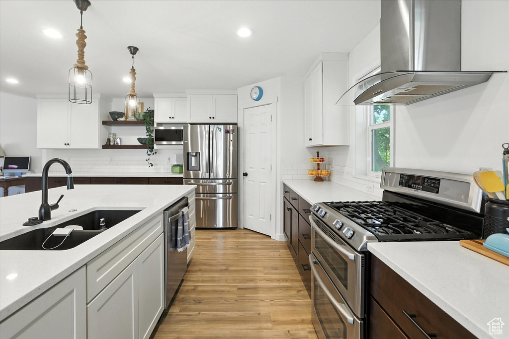 Kitchen with range hood, appliances with stainless steel finishes, open shelves, light countertops, and recessed lighting