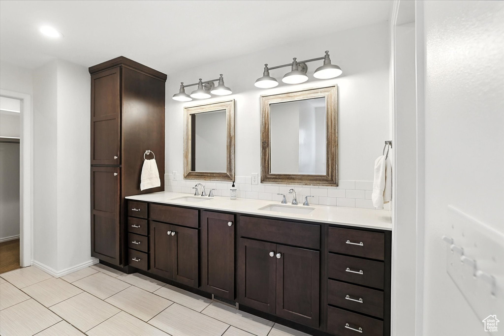 Full bath featuring double vanity, backsplash, and tile patterned flooring