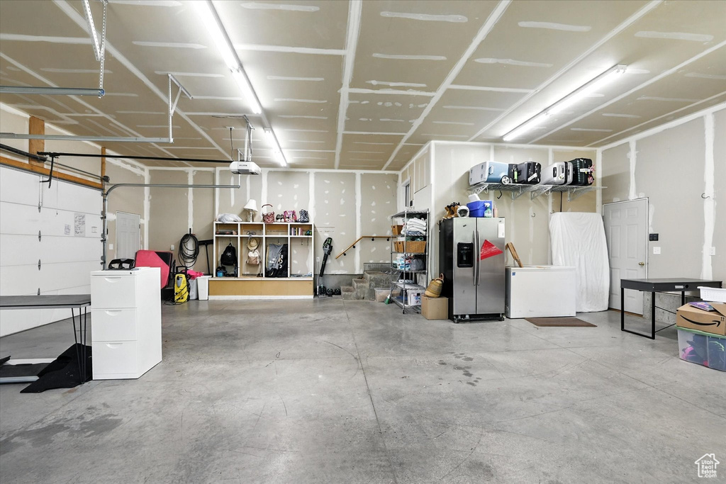 Garage featuring stainless steel fridge with ice dispenser, refrigerator, and a garage door opener