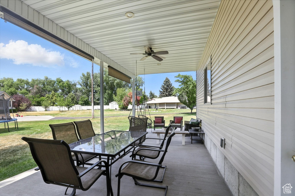 View of patio featuring a trampoline, outdoor dining area, and ceiling fan