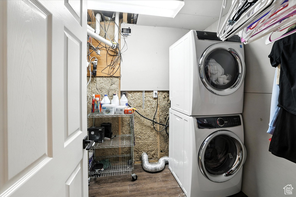 Laundry area featuring stacked washer and clothes dryer and wood finished floors