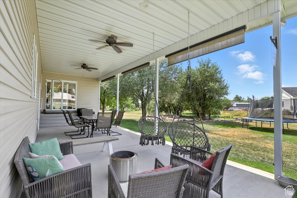 View of patio with outdoor dining area, a trampoline, and ceiling fan