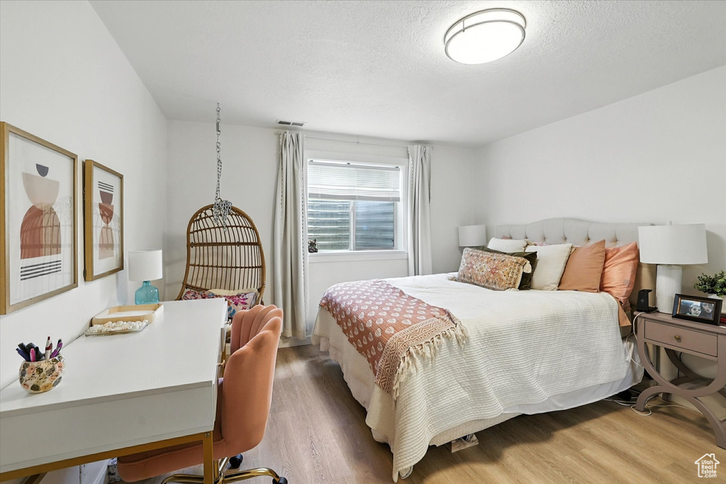 Bedroom with wood finished floors and a textured ceiling
