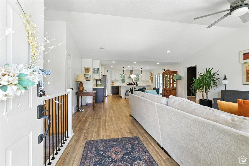 Living room with light wood-type flooring, lofted ceiling, a ceiling fan, and recessed lighting
