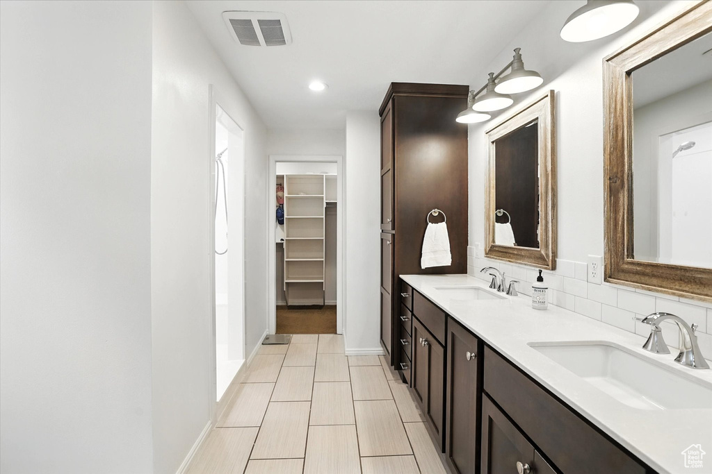 Full bath with double vanity, a spacious closet, and recessed lighting