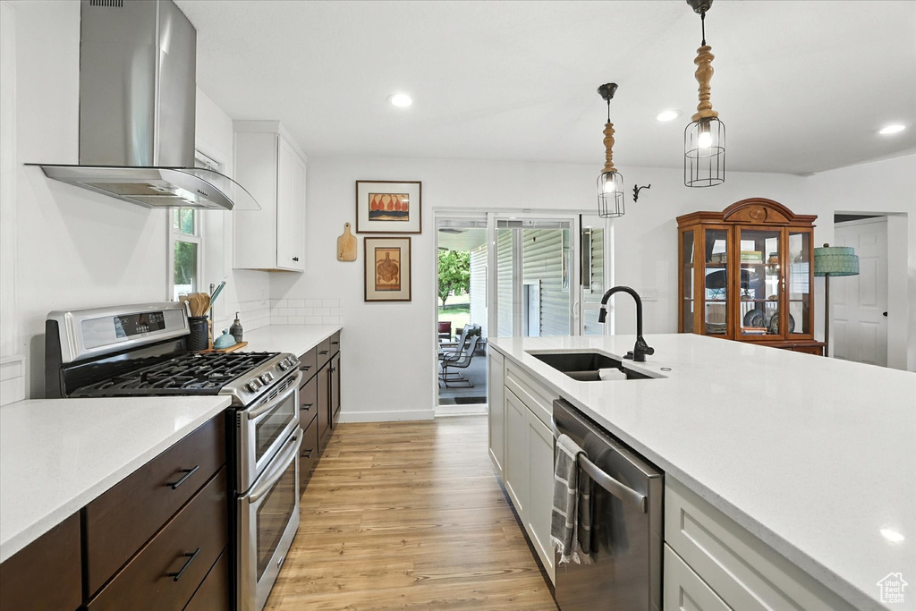 Kitchen with extractor fan, stainless steel appliances, light wood finished floors, light countertops, and recessed lighting