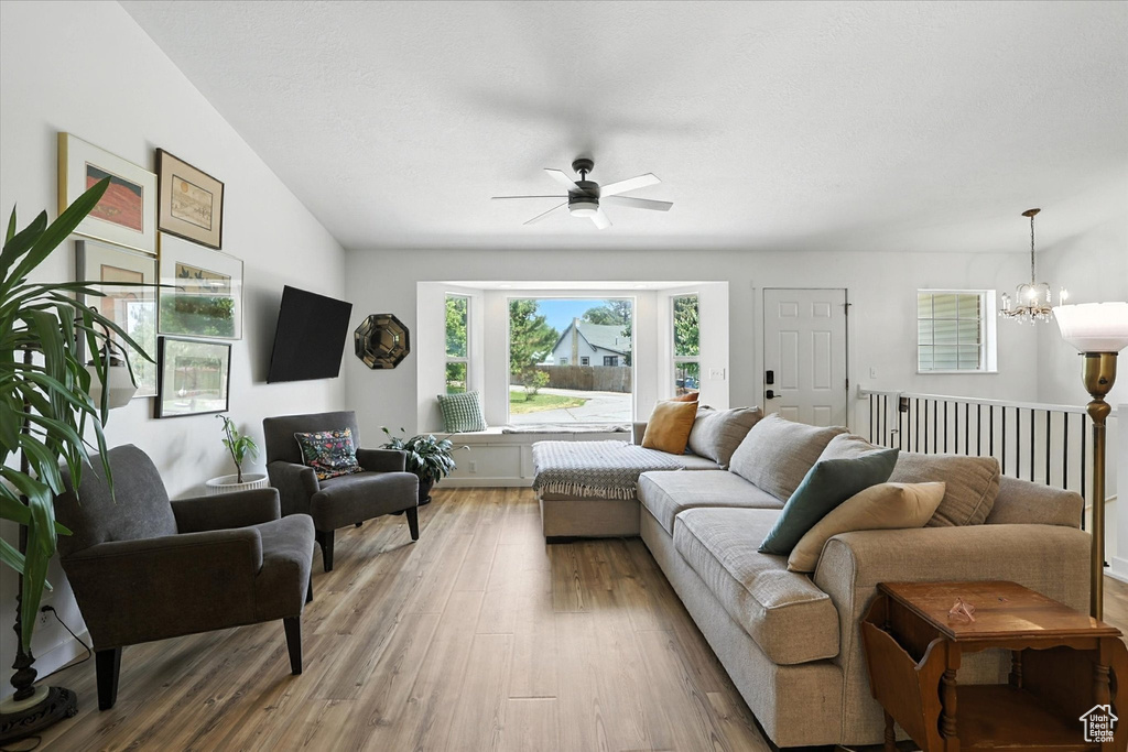 Living area with ceiling fan, light wood finished floors, and a chandelier