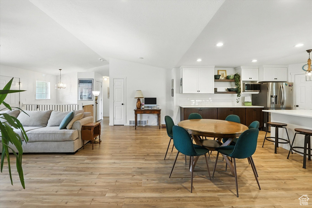 Dining area with lofted ceiling, a chandelier, light wood-style flooring, and recessed lighting