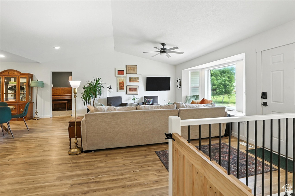 Living room with ceiling fan, lofted ceiling, light wood finished floors, and recessed lighting