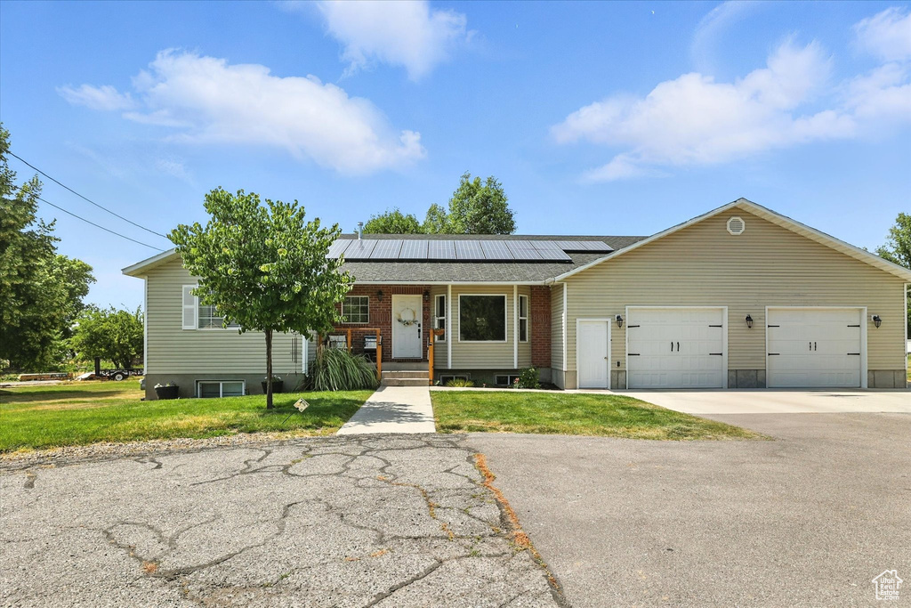 View of front facade with roof mounted solar panels, a front lawn, a garage, and concrete driveway