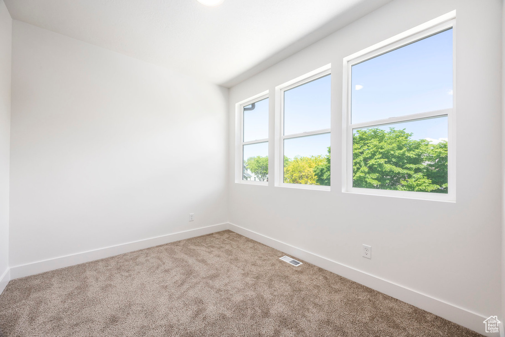 Carpeted spare room featuring baseboards