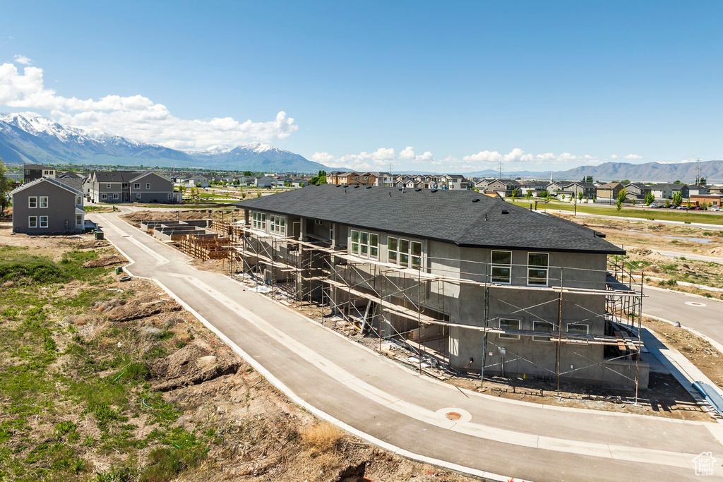 Back of house with a mountain view, roof with shingles, and a residential view
