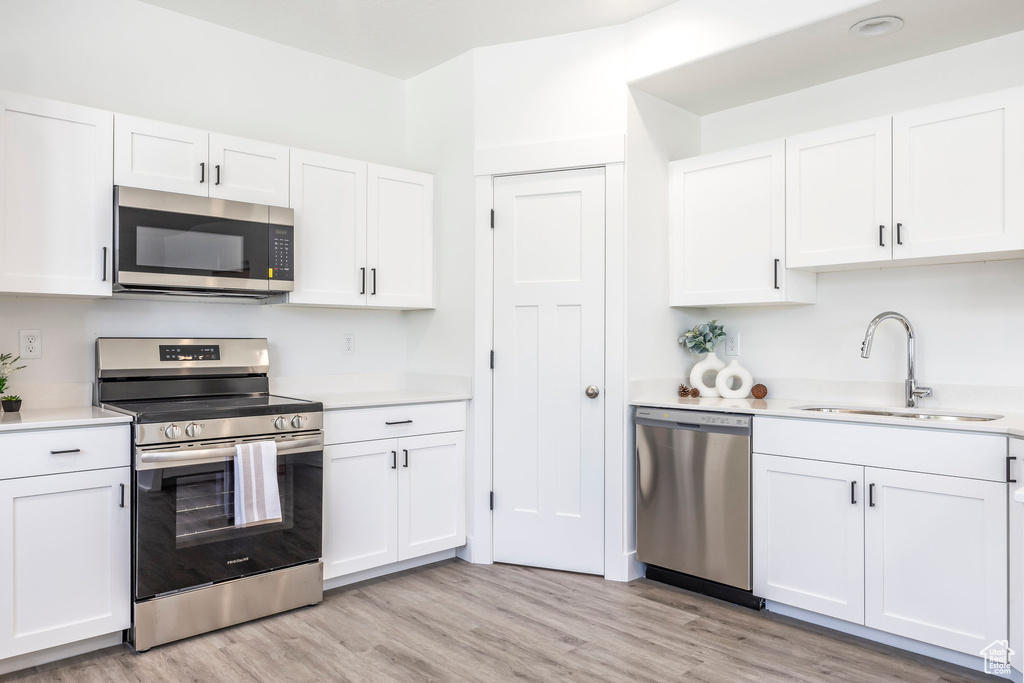 Kitchen with stainless steel appliances, light countertops, and white cabinetry