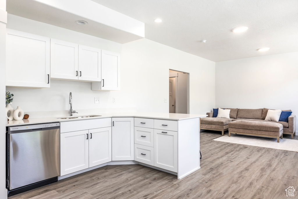 Kitchen featuring dishwasher, light wood finished floors, a peninsula, light countertops, and white cabinetry