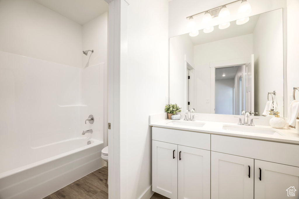 Full bathroom featuring double vanity, shower / bath combination, and wood finished floors