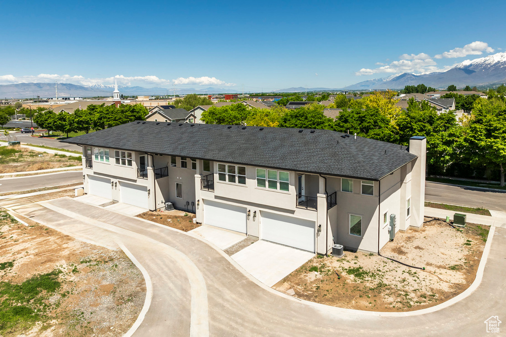 Ranch-style house with an attached garage, roof with shingles, stucco siding, a balcony, and a chimney