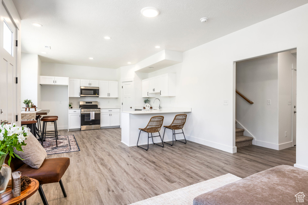 Living room with light wood-style floors, stairway, and recessed lighting