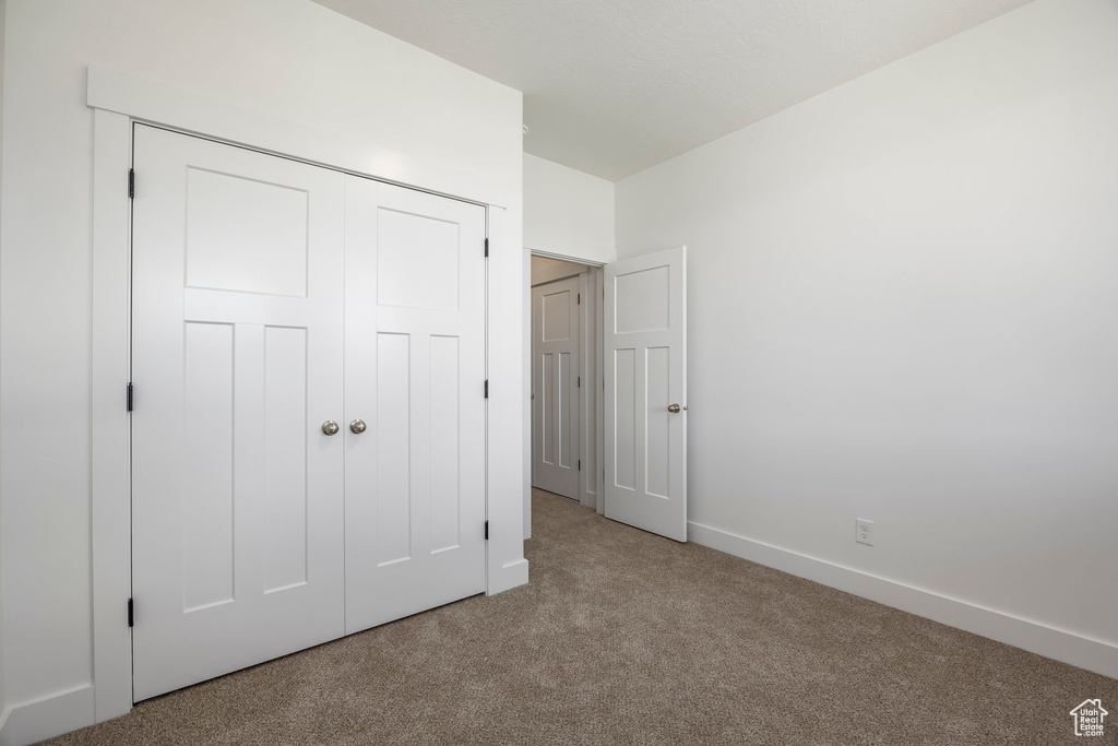 Unfurnished bedroom featuring carpet and a closet