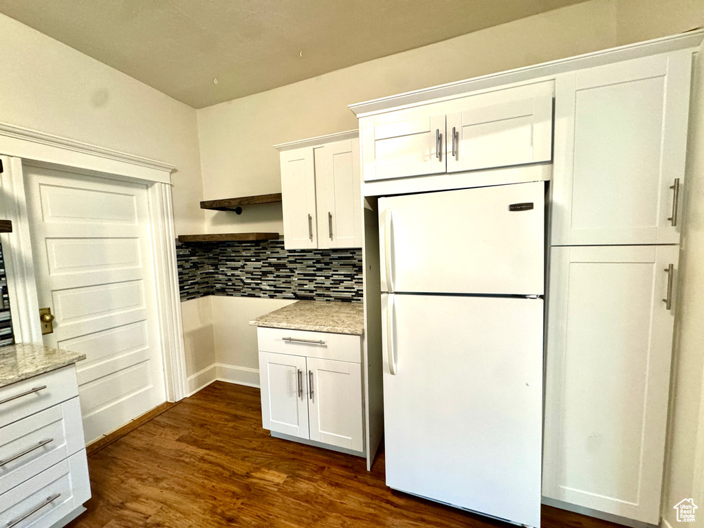 Kitchen featuring freestanding refrigerator, white cabinets, open shelves, tasteful backsplash, and dark wood-style floors