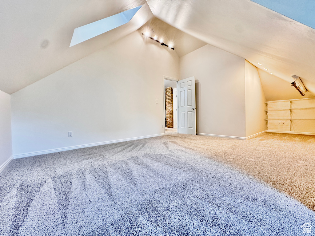 Additional living space featuring a skylight, carpet floors, and lofted ceiling