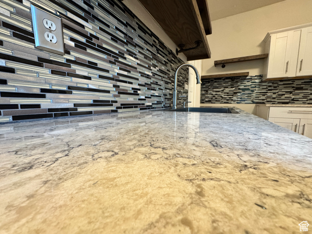 Kitchen view of backsplash, white cabinets, and light stone counters