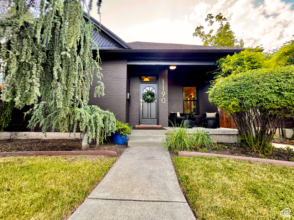 View of front of house featuring brick siding, covered porch, and a front yard