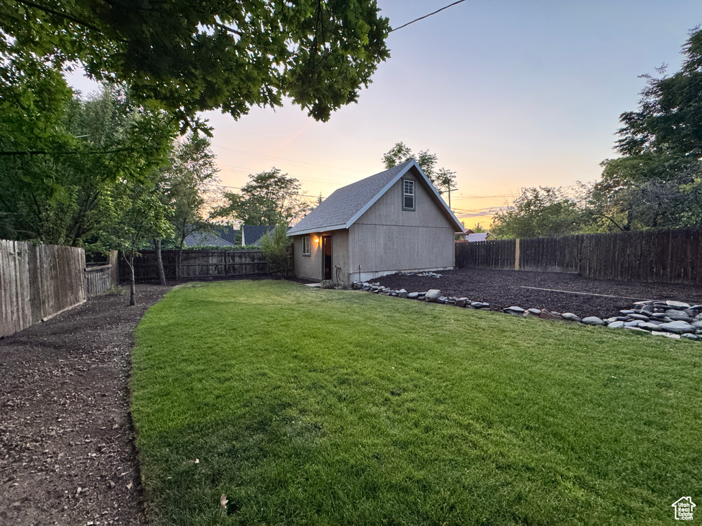 Yard at dusk with a fenced backyard and an outdoor structure