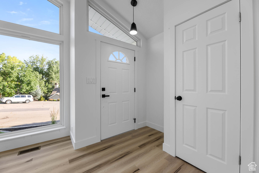 Foyer entrance with light wood-style flooring and lofted ceiling