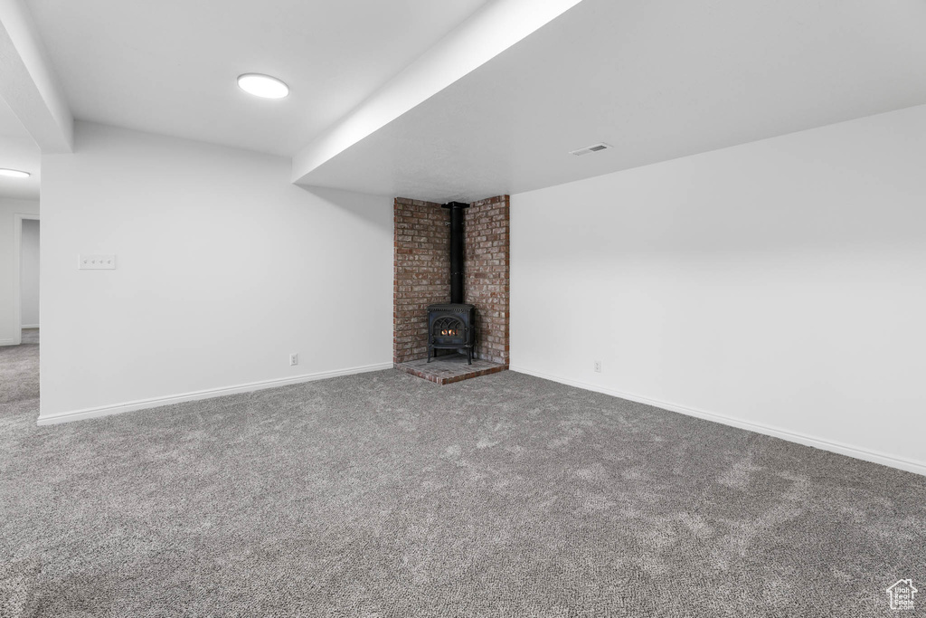 Unfurnished living room featuring carpet and a wood stove