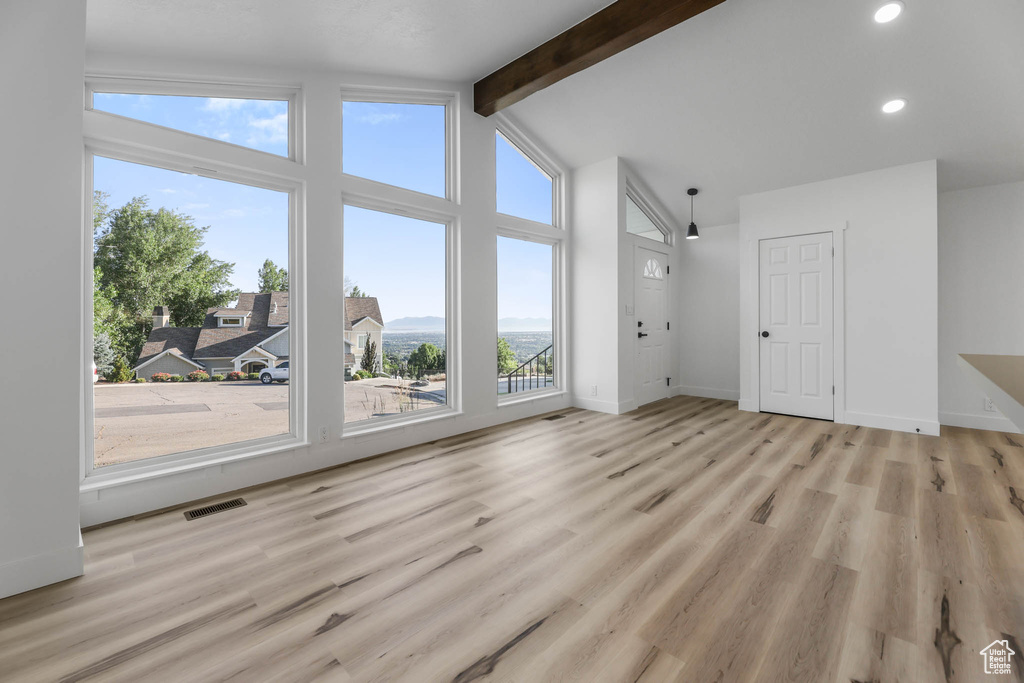 Unfurnished living room featuring beam ceiling, recessed lighting, light wood-type flooring, and high vaulted ceiling